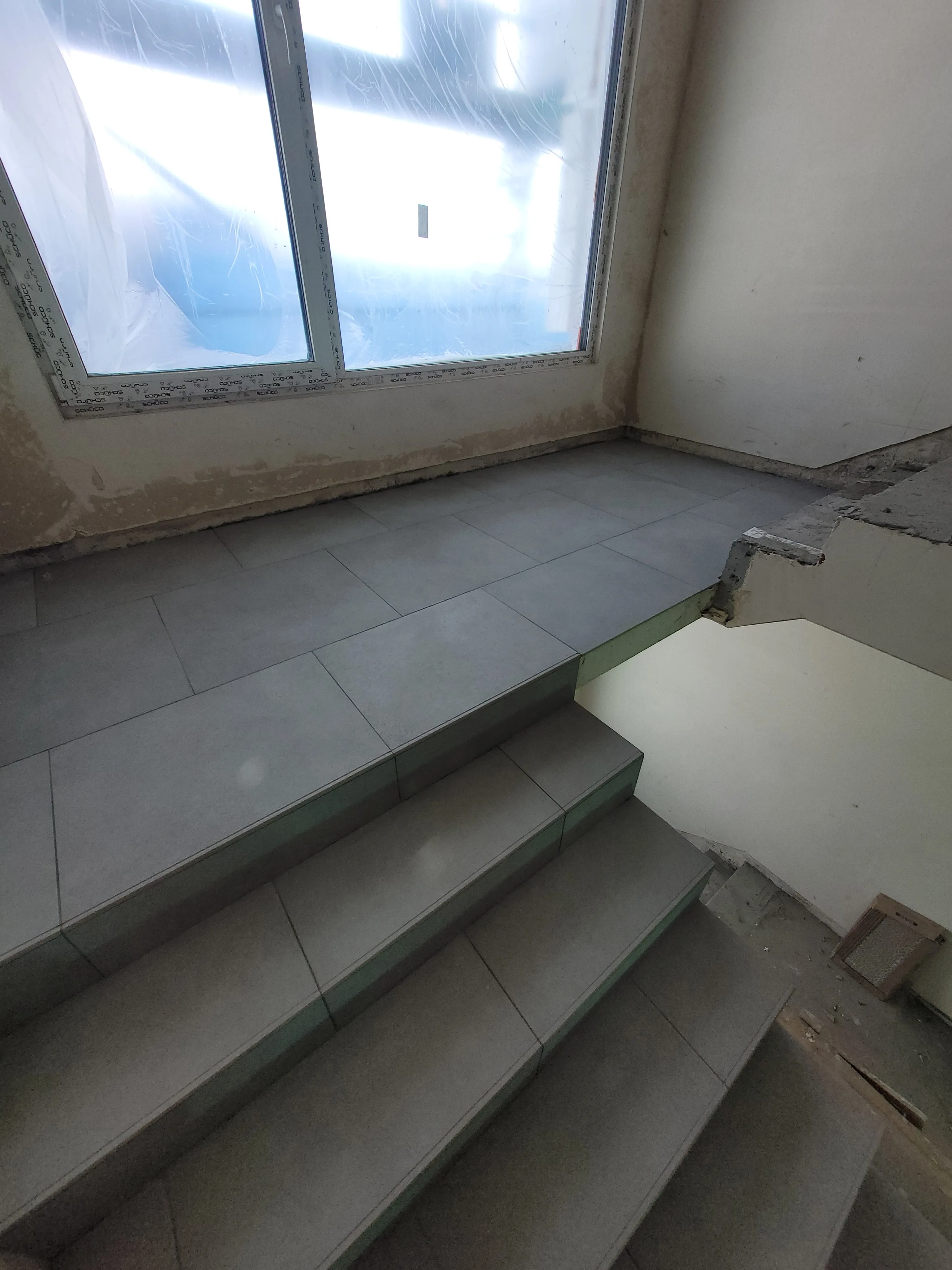 Widok schodów pokrytych płytkami gresowymi w trakcie remontu wnętrza