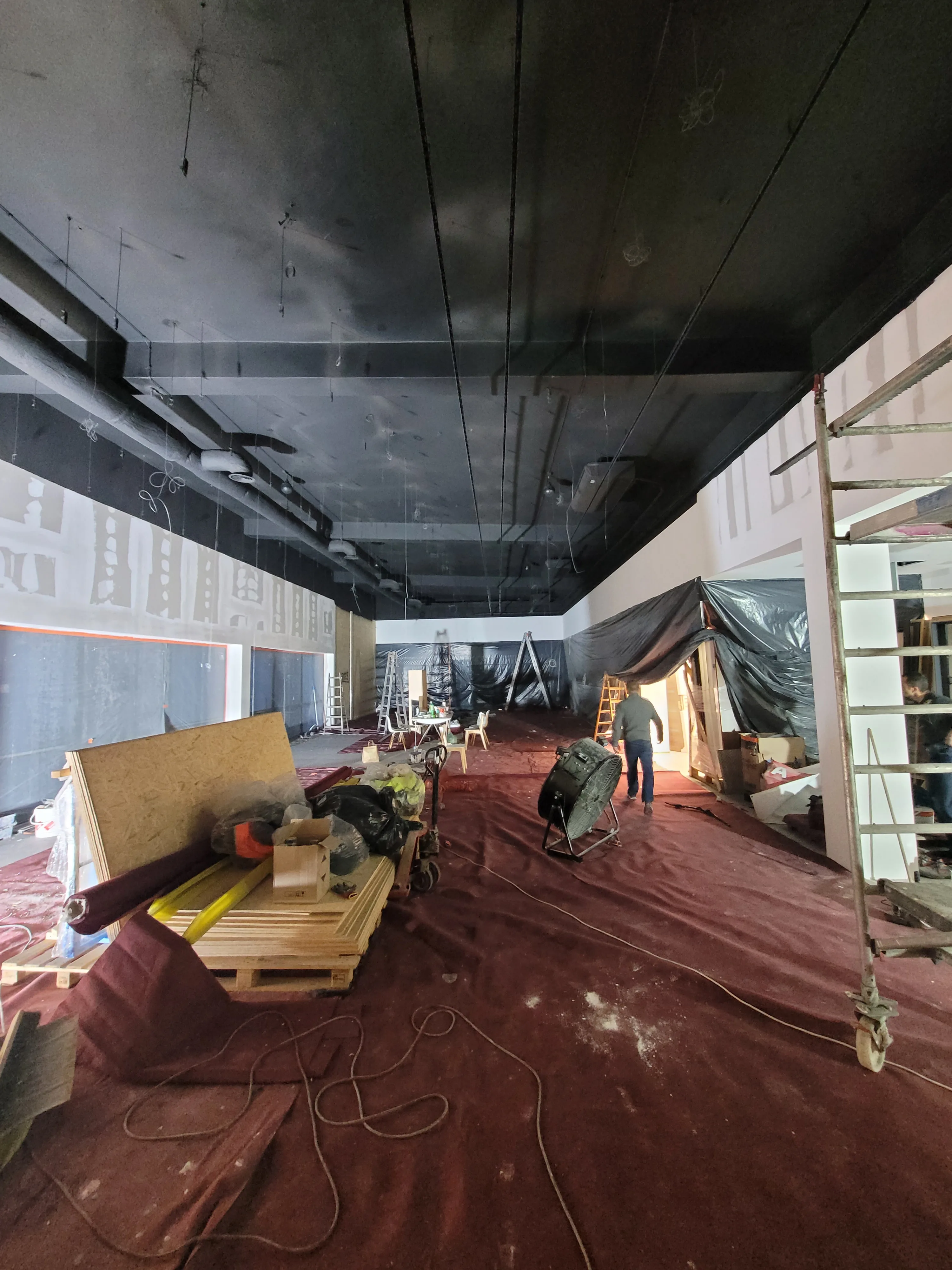 Przestrzeń komercyjna w trakcie adaptacji, widać rusztowania i materiały budowlane